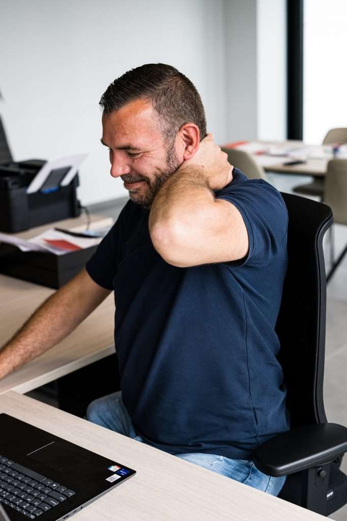 Man werkend op laptop met pijn in de nek door niet op een ergonomische bureaustoel te zitten